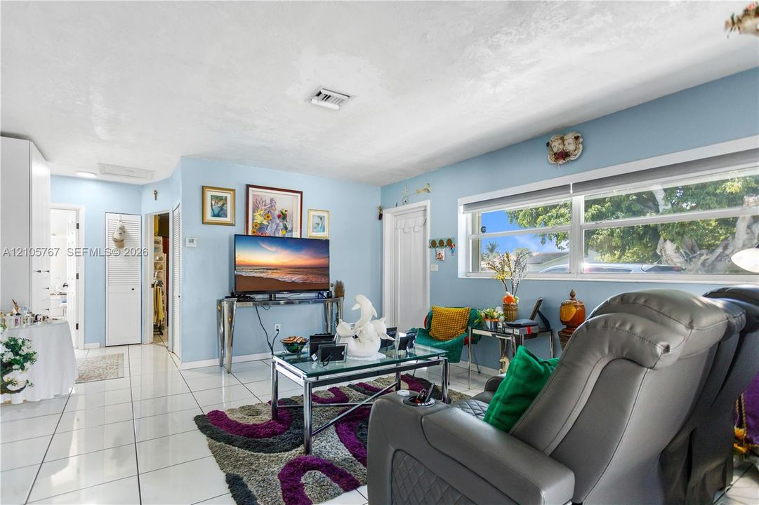 Bright living area featuring large-format ceramic tile flooring, expansive horizontal windows, and solid-core interior doors