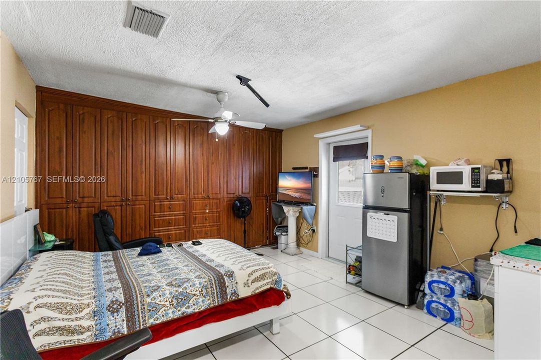 Extensive floor-to-ceiling wood cabinetry, ceramic tile flooring, and a ceiling-mounted fan
