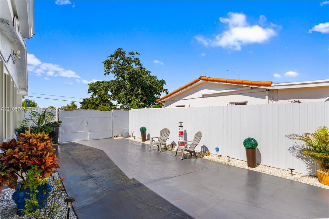 Private outdoor patio featuring stamped concrete flooring, tall privacy fencing, and double-gate access