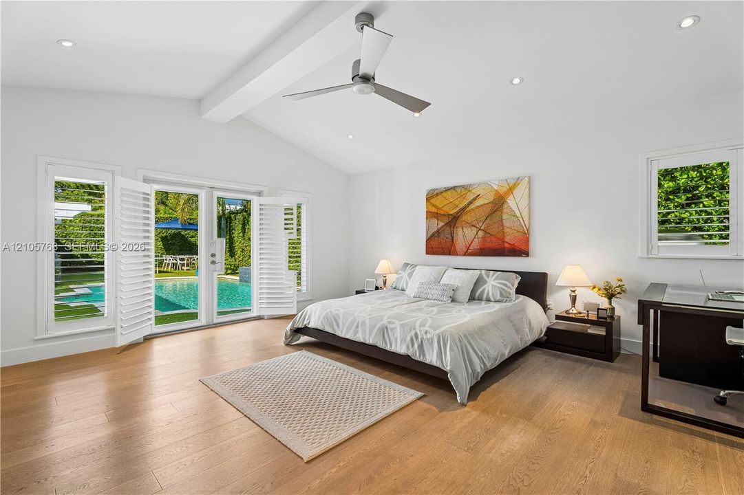 Vaulted ceilings, wood-finish flooring, recessed lighting, ceiling fan, and double glass-paneled doors featuring plantation shutters