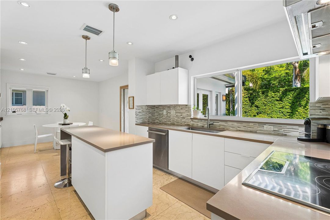 Kitchen featuring flat-panel cabinetry, quartz countertops, stone tile backsplash, stainless steel appliances, and large-format tile flooring