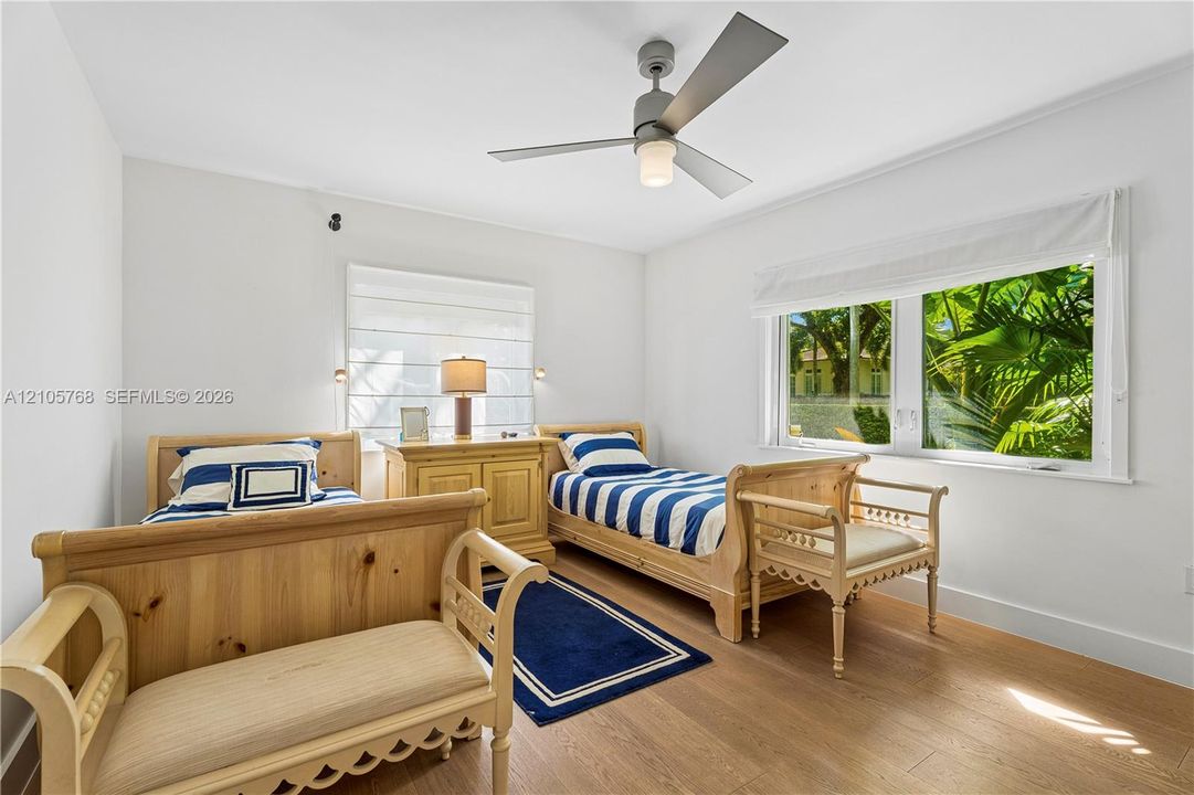 Interior space featuring wood-finish flooring, a modern three-blade ceiling fan, white wall finishes, and large windows with integrated shades