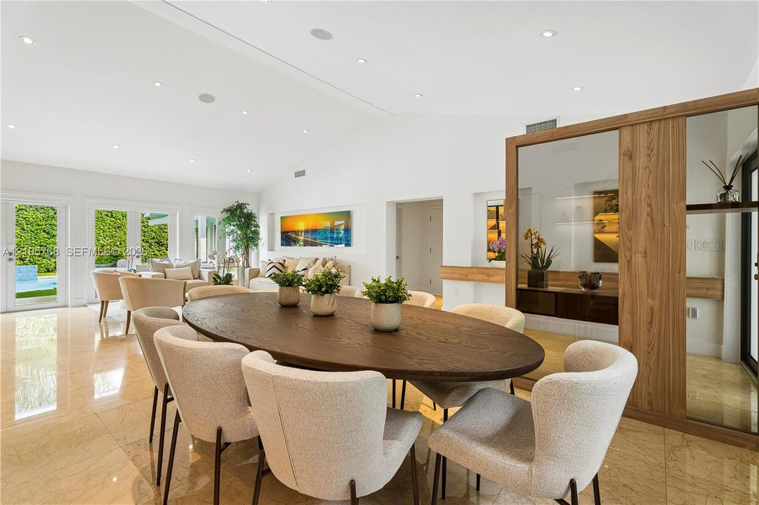 Open-concept living space featuring vaulted ceilings, recessed lighting, polished stone flooring, and a built-in wood-framed display partition