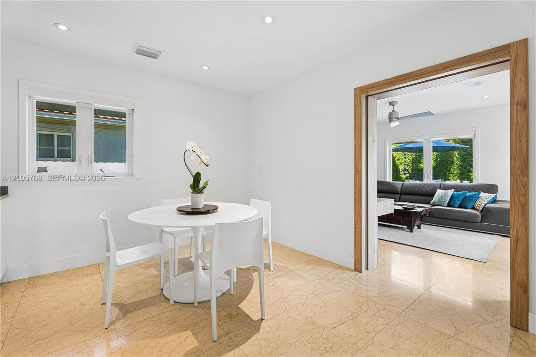 Polished stone flooring, recessed lighting, and wooden door casing framing the entryway