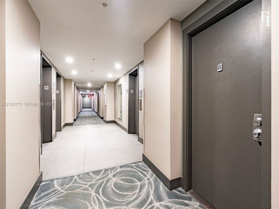 Common hallway featuring neutral wall finishes, large-format tile flooring, recessed ceiling lighting, and patterned wall-to-wall carpeting