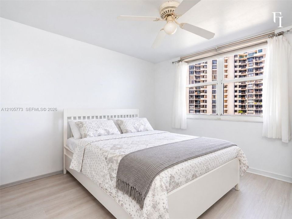 Neutral interior featuring wood-finish flooring, white walls, and a ceiling fan with integrated lighting
