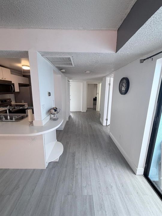 Kitchen featuring white cabinetry, wood-finish flooring, and a curved peninsula countertop