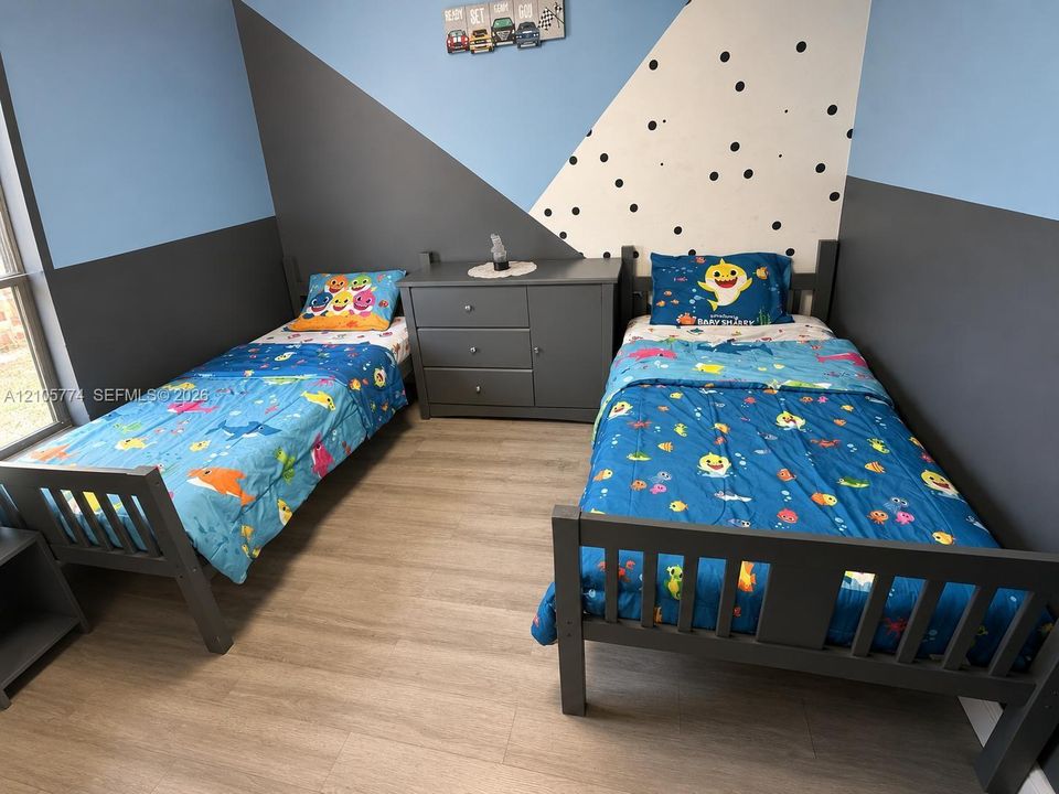 Room with geometric wall accents, wood-finish flooring, and natural light from a vertical window