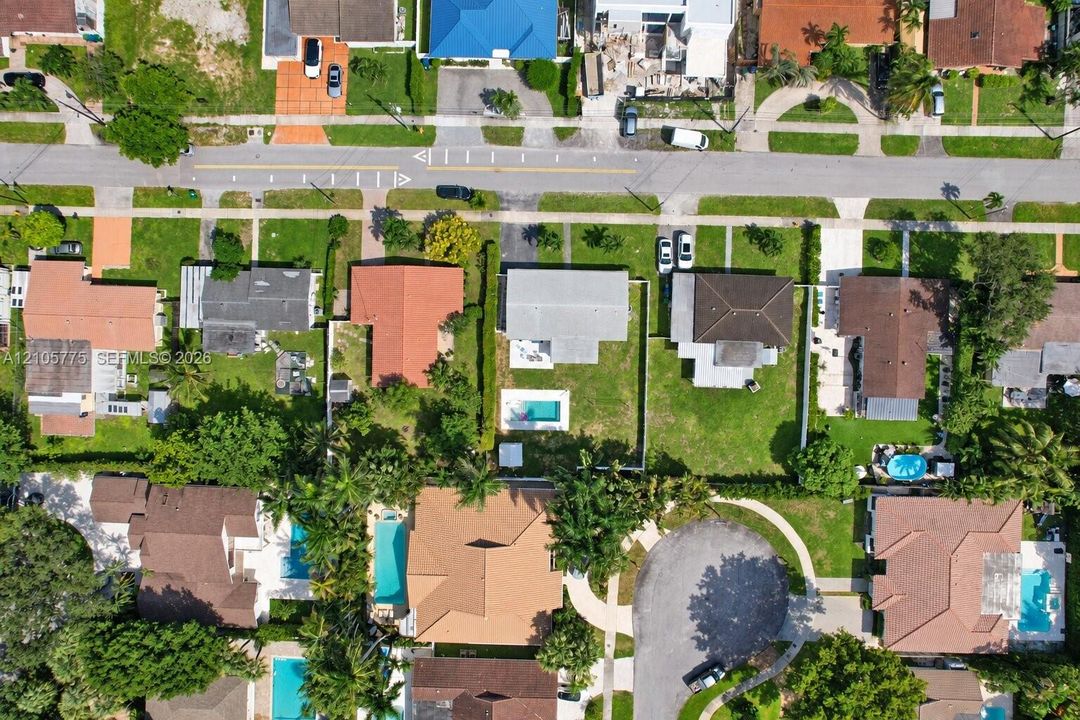 Aerial perspective of a single-family property featuring a rectangular in-ground swimming pool, a fully fenced backyard, and a concrete driveway