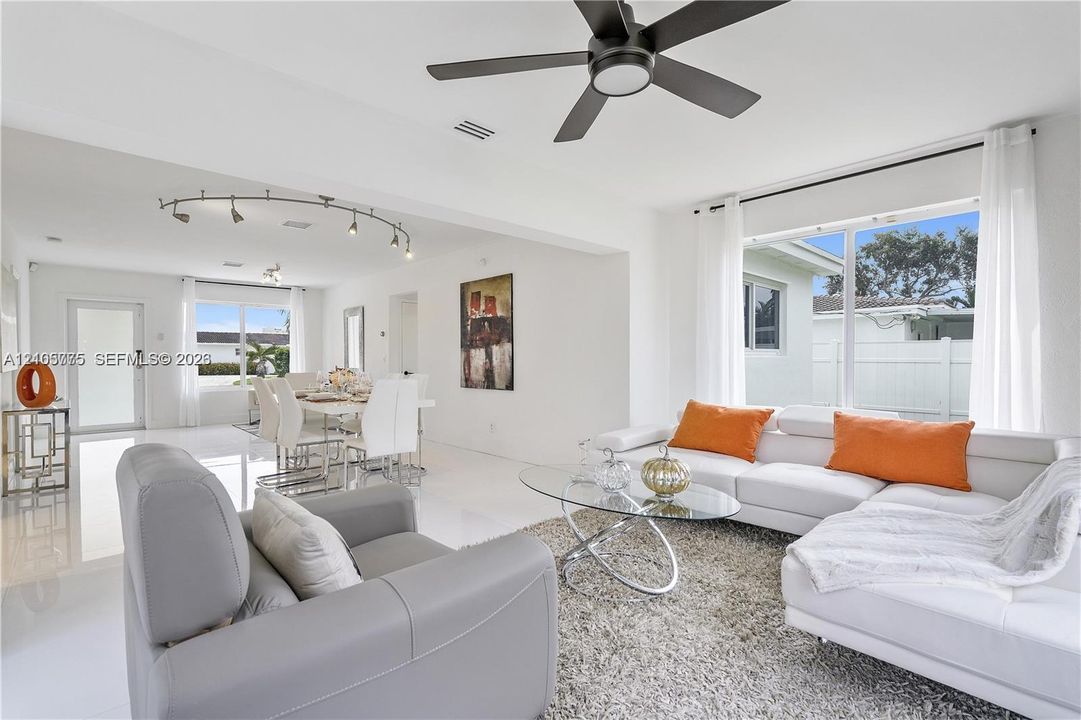 Open-concept interior featuring large-format tile flooring, matte black ceiling fan, and adjustable track lighting