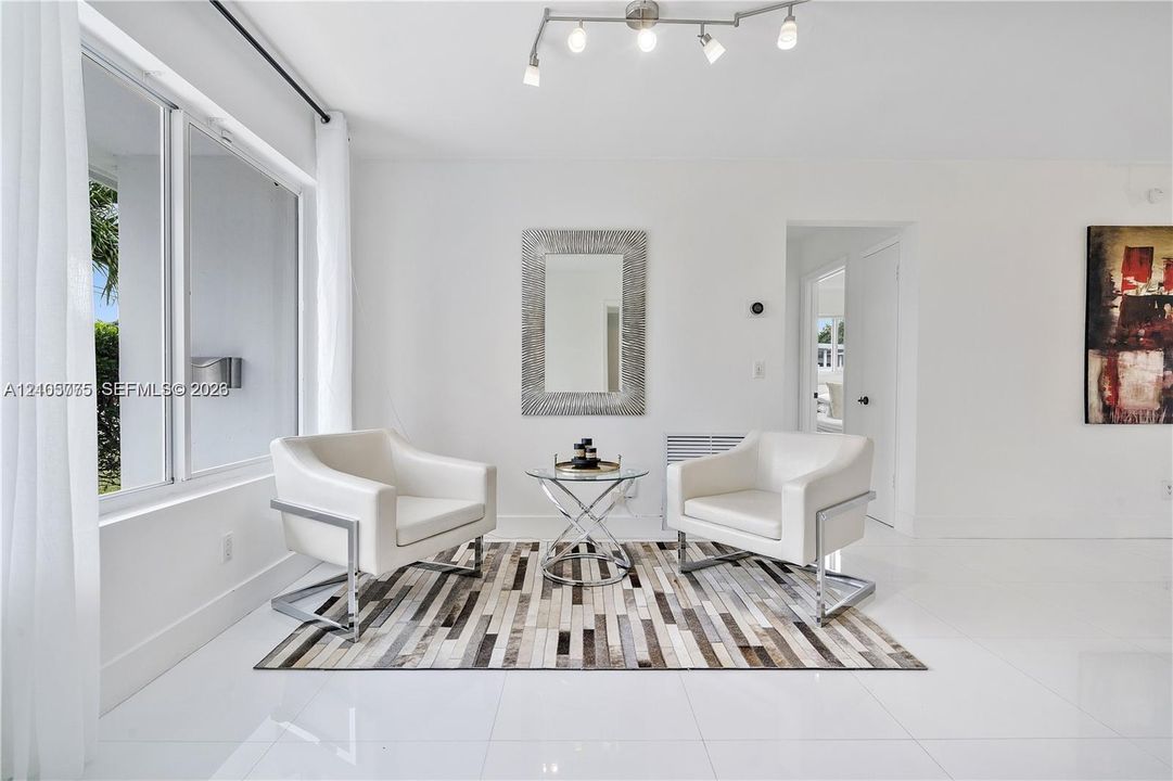 Bright interior space featuring polished tile flooring, large multi-pane windows, and a multi-bulb track lighting fixture