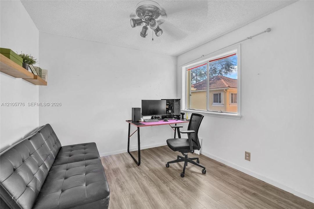 Wood-finish flooring, sliding window, ceiling fan with integrated lighting, and wall-mounted shelving