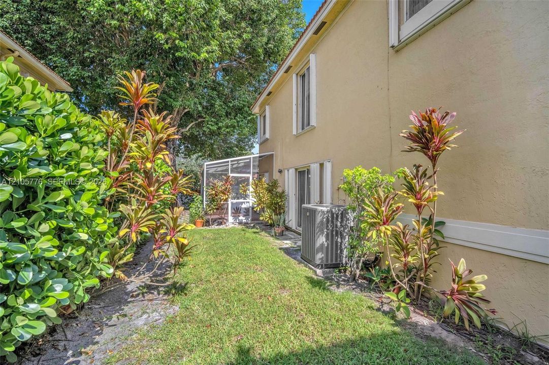 Stucco exterior siding, landscaped lawn, mature trees, and a screened-in lanai
