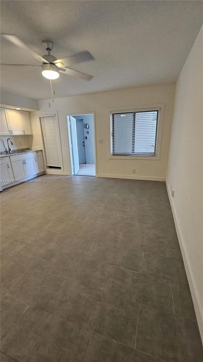 Large-format tile flooring, white cabinetry, integrated ceiling fan with light fixture, and horizontal window blinds