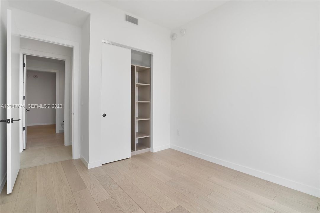 Neutral interior featuring wood-finish flooring, sliding closet doors, and built-in shelving