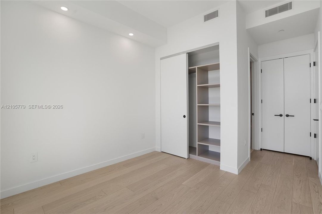 Room featuring wood-finish flooring, recessed lighting, and a closet with built-in shelving