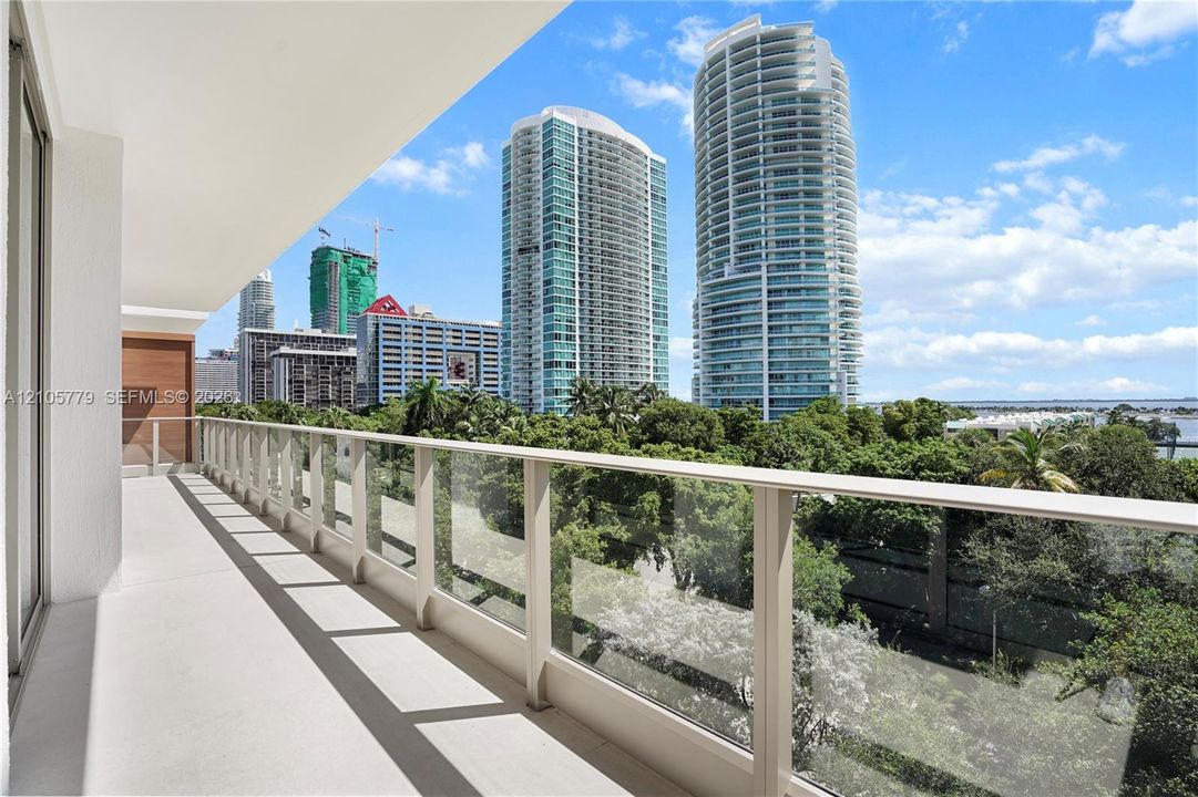 Covered balcony with smooth concrete flooring and a transparent glass panel railing
