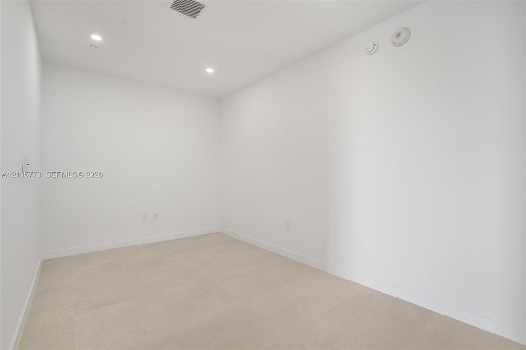 Interior space featuring neutral stone-finish flooring, crisp white walls, and recessed ceiling lighting