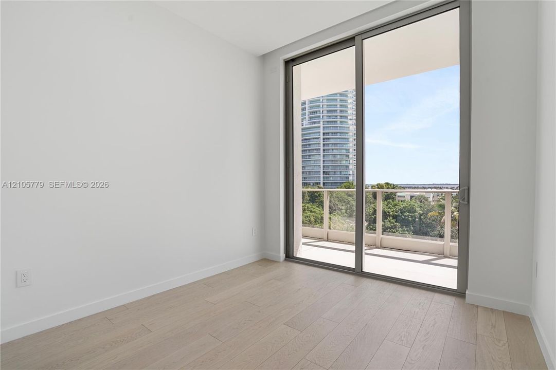 Wood-finish flooring, floor-to-ceiling sliding glass doors, and access to a private balcony