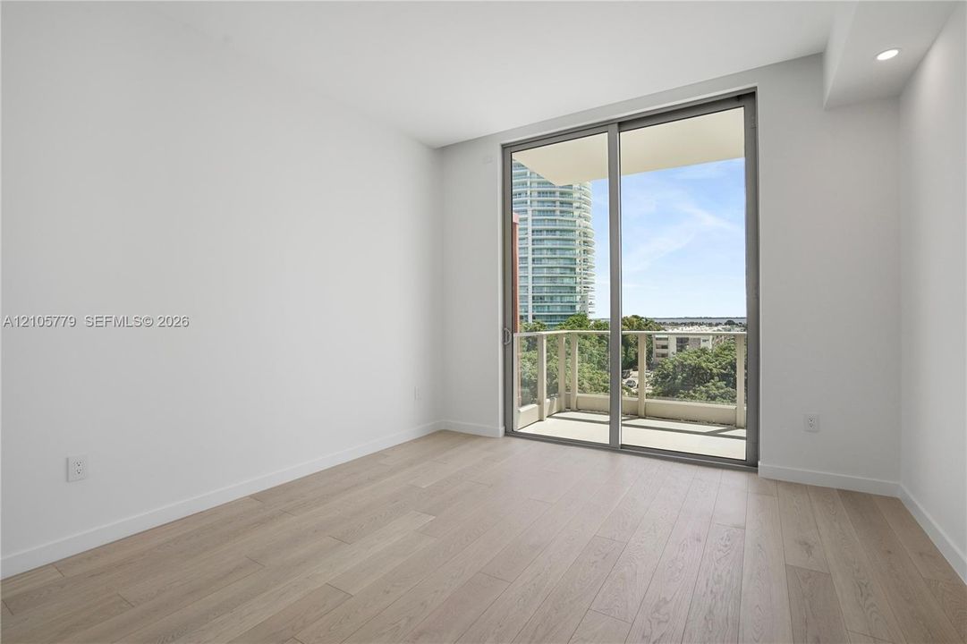 Room featuring wood-finish flooring, recessed lighting, and a sliding glass door providing access to a private balcony with railing