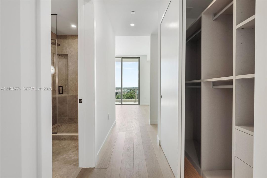 Hallway featuring light-toned wood-finish flooring, recessed lighting, and custom built-in cabinetry with integrated shelving and drawers