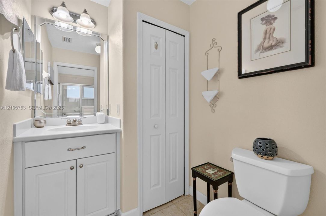 White vanity featuring a solid surface countertop, undermount sink, and polished metal hardware, paired with a bi-fold closet door and wall-mounted light fixture