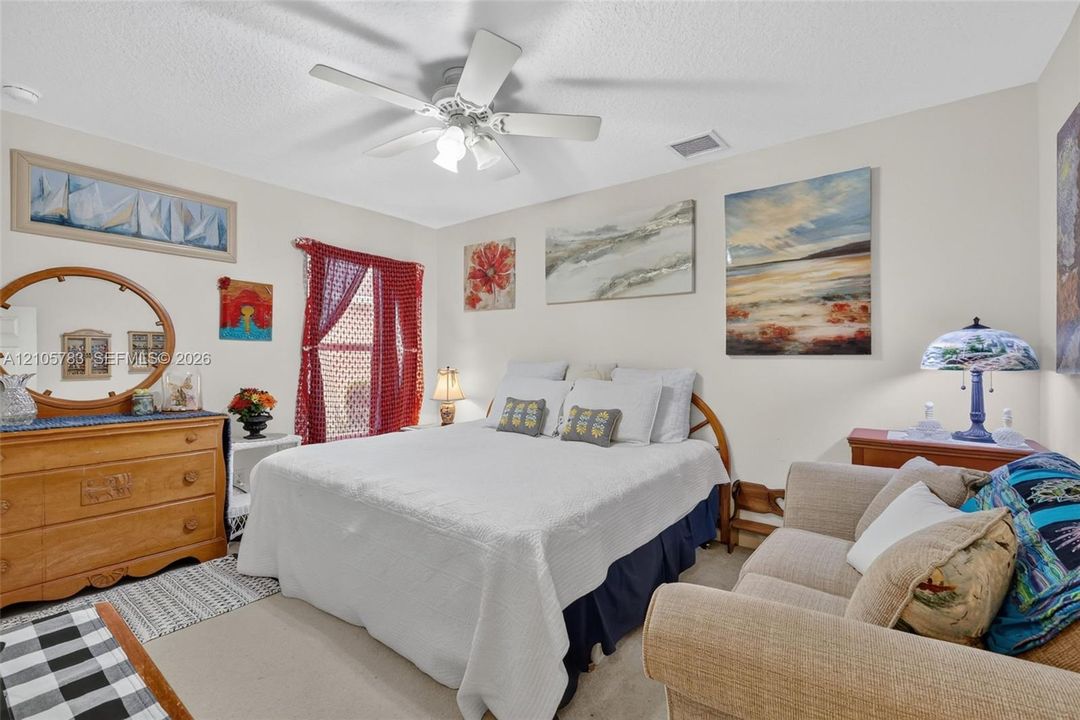 Neutral wall tones, carpeted flooring, and a multi-blade ceiling fan with integrated lighting