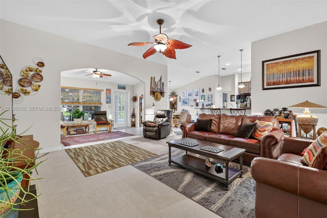 Vaulted ceilings, arched room entry, leaf-style ceiling fan, neutral wall tones, and recessed lighting