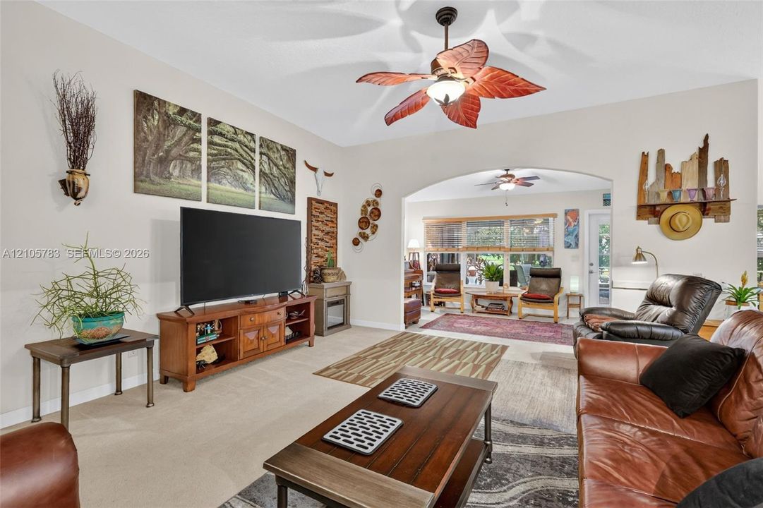 Vaulted ceilings with a decorative ceiling fan, featuring a neutral color palette and a prominent arched entryway