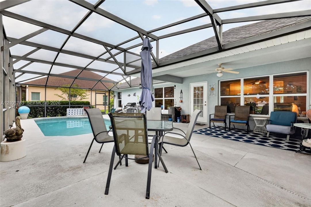 Screen-enclosed patio featuring a concrete deck, swimming pool, and ceiling-mounted fan