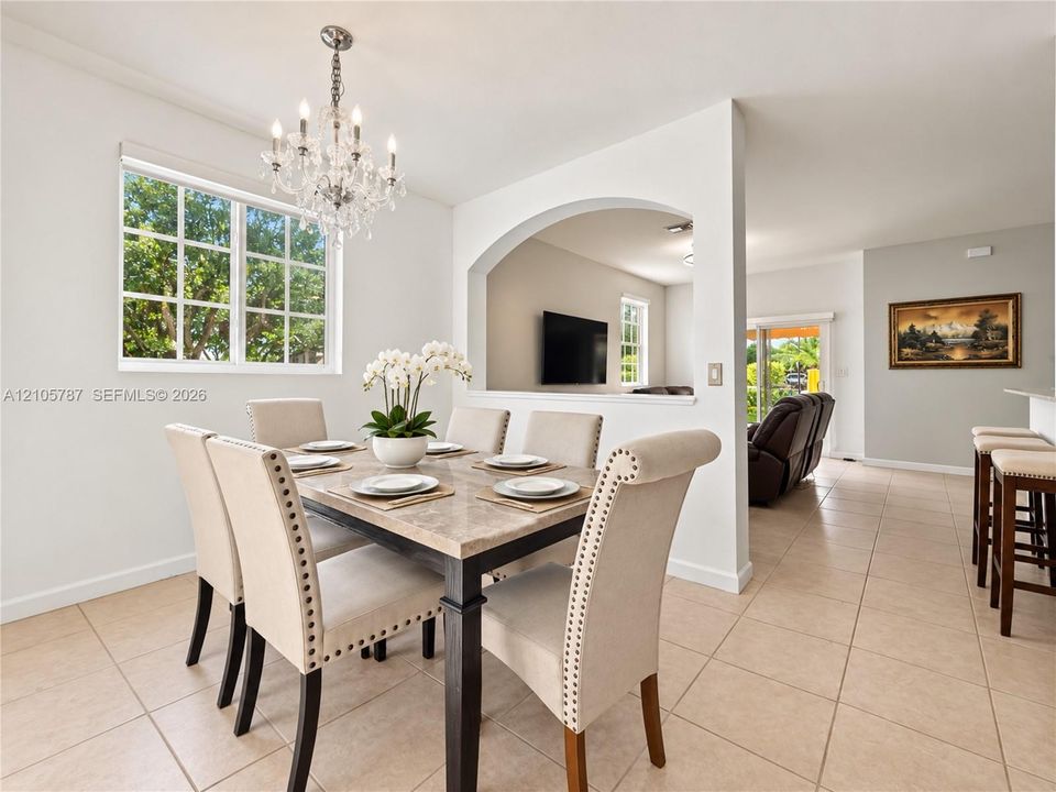 Dining area featuring a multi-pane window, crystal chandelier, arched architectural opening, and ceramic tile flooring
