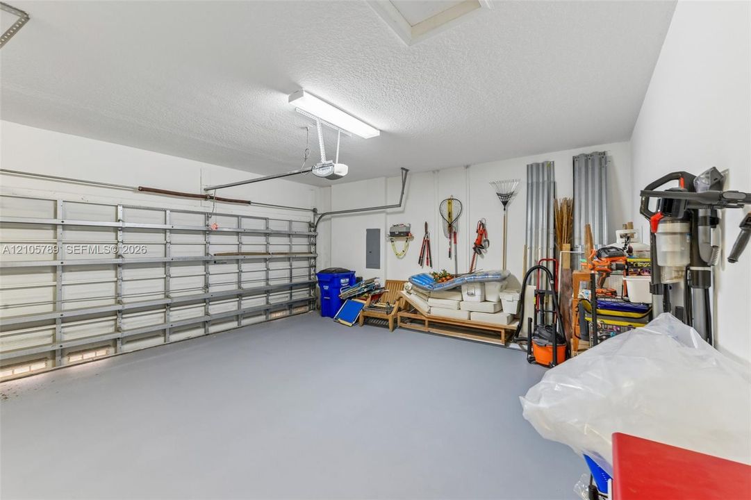 Enclosed garage featuring a metal overhead door, finished flooring, an integrated ceiling light fixture, and an automated door opener