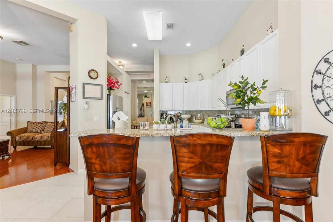Kitchen featuring white cabinetry, stone-surface breakfast bar, recessed lighting, and stainless steel appliances