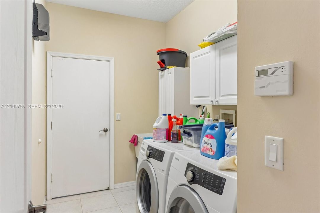 Laundry room featuring white wall-mounted cabinetry, tile flooring, and a built-in utility sink