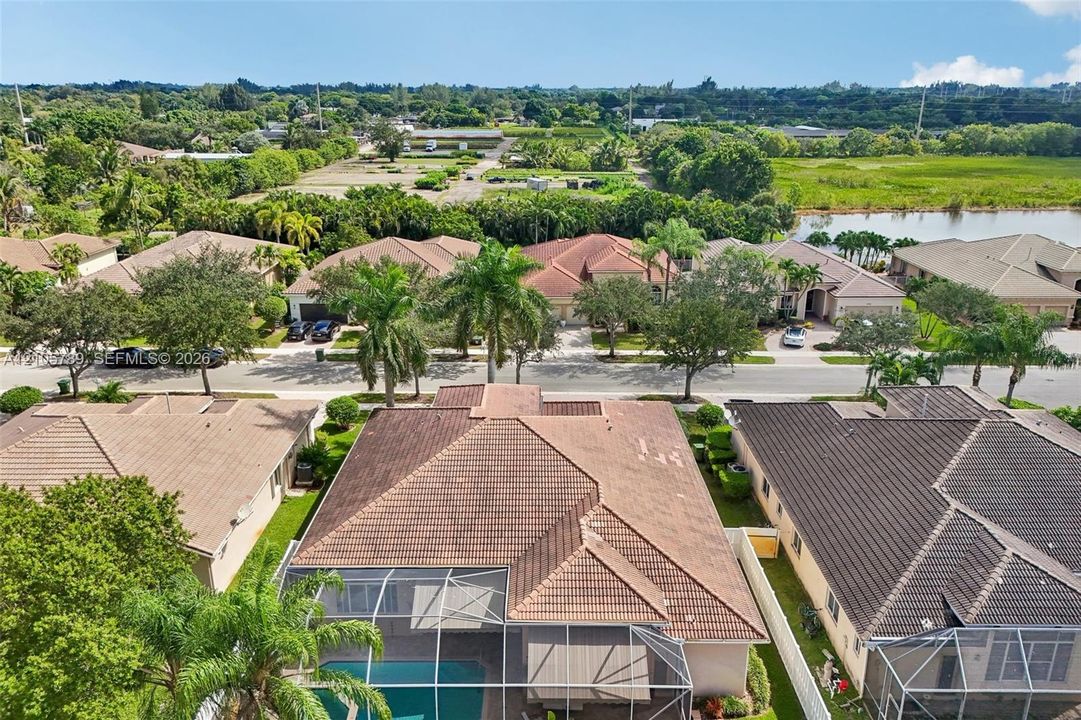Aerial perspective featuring a tile roof, an enclosed swimming pool, mature palm trees, and native vegetation