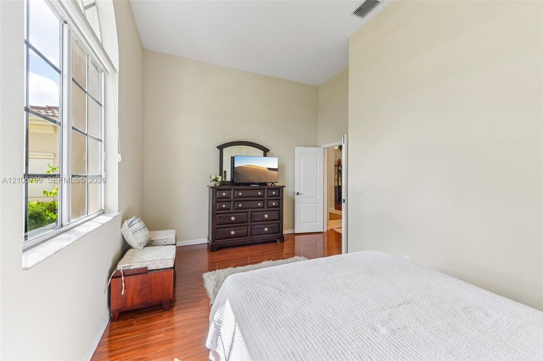 High ceilings featuring a large arched window with grid detailing and polished wood-finish flooring