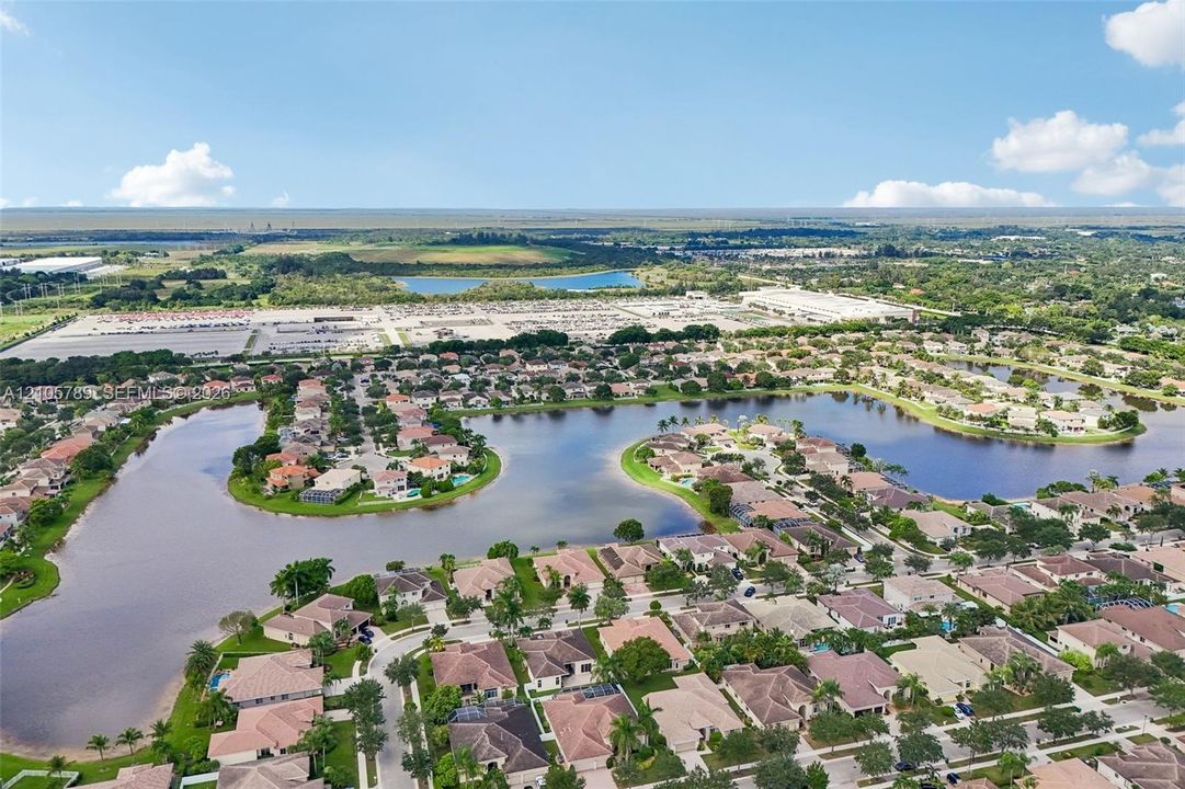Aerial perspective of a residential community featuring extensive waterfront acreage, winding roadways, uniform tile roofing, and mature perimeter landscaping