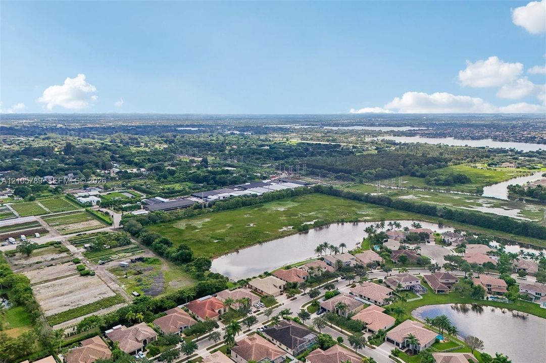 Aerial perspective showcasing surrounding natural bodies of water, extensive green space, and mature tree clusters