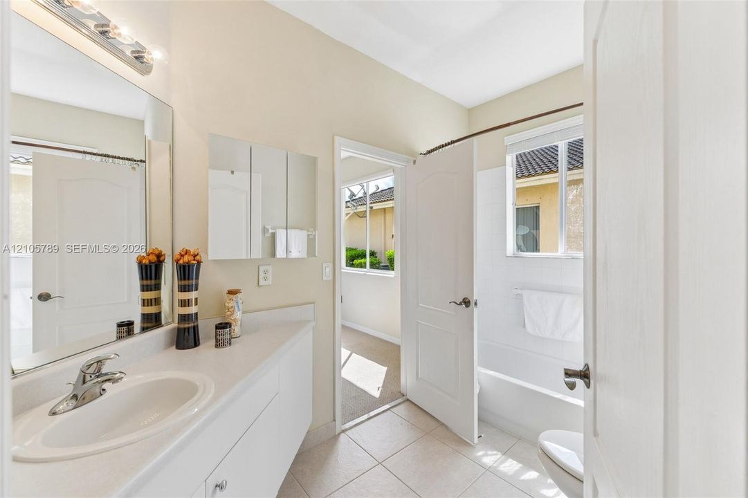 Bathroom featuring a vanity with a white solid-surface countertop, an integrated oval basin, a chrome faucet, and a large wall-mounted mirror