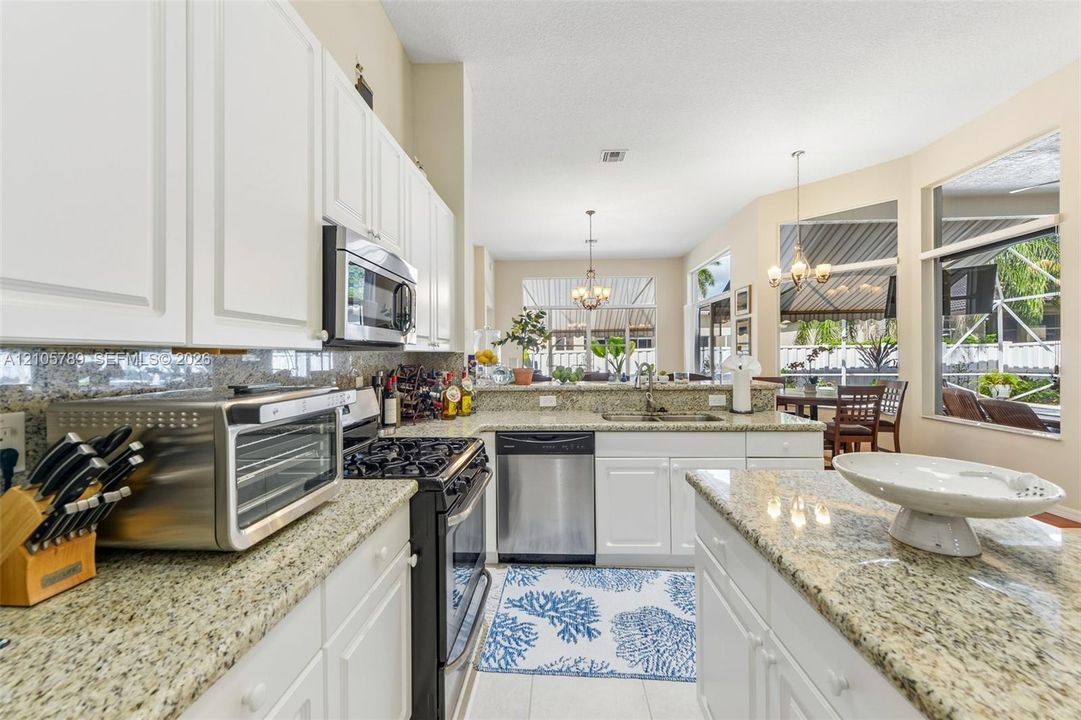 Kitchen featuring white cabinetry, stone countertops, stainless steel appliances, a center island, and expansive windows