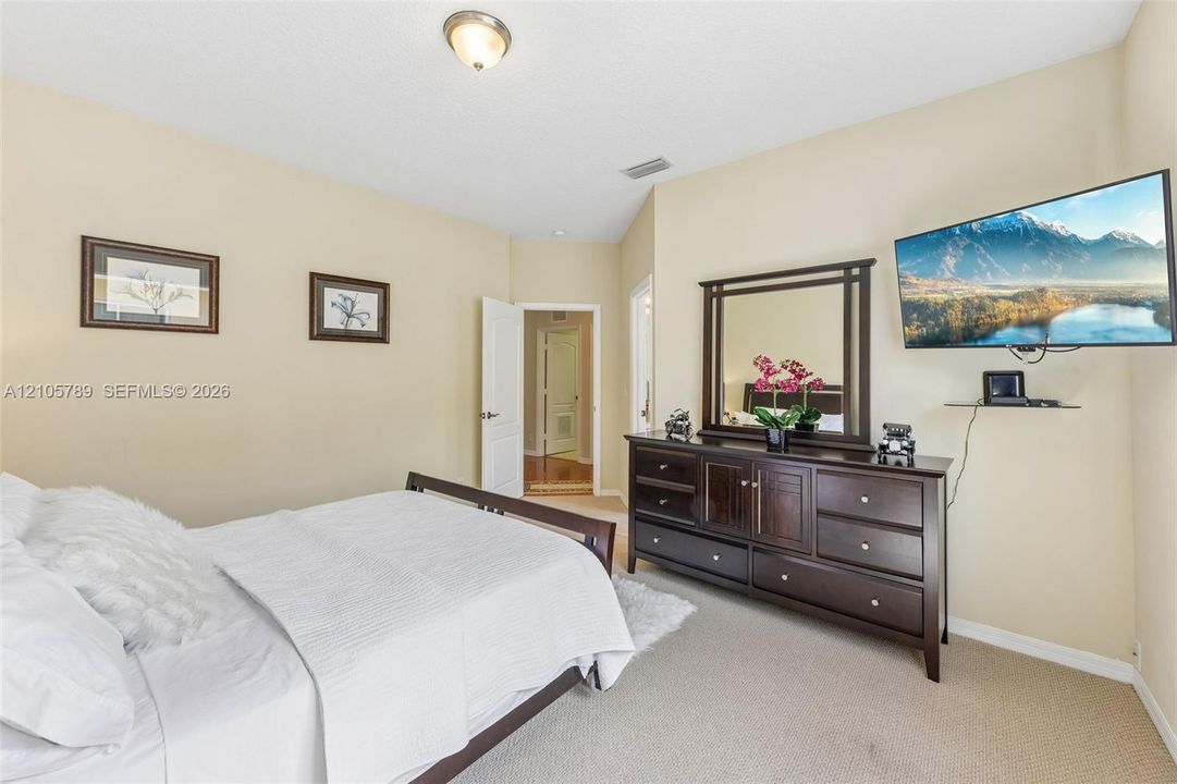 Neutral-toned interior space featuring vaulted ceilings, wall-to-wall carpeting, and a central ceiling-mounted light fixture
