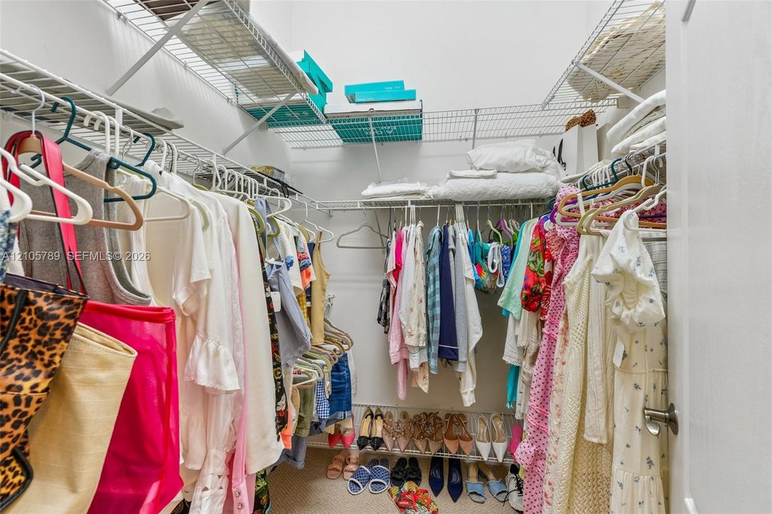 Walk-in storage space featuring multi-tiered white wire shelving systems