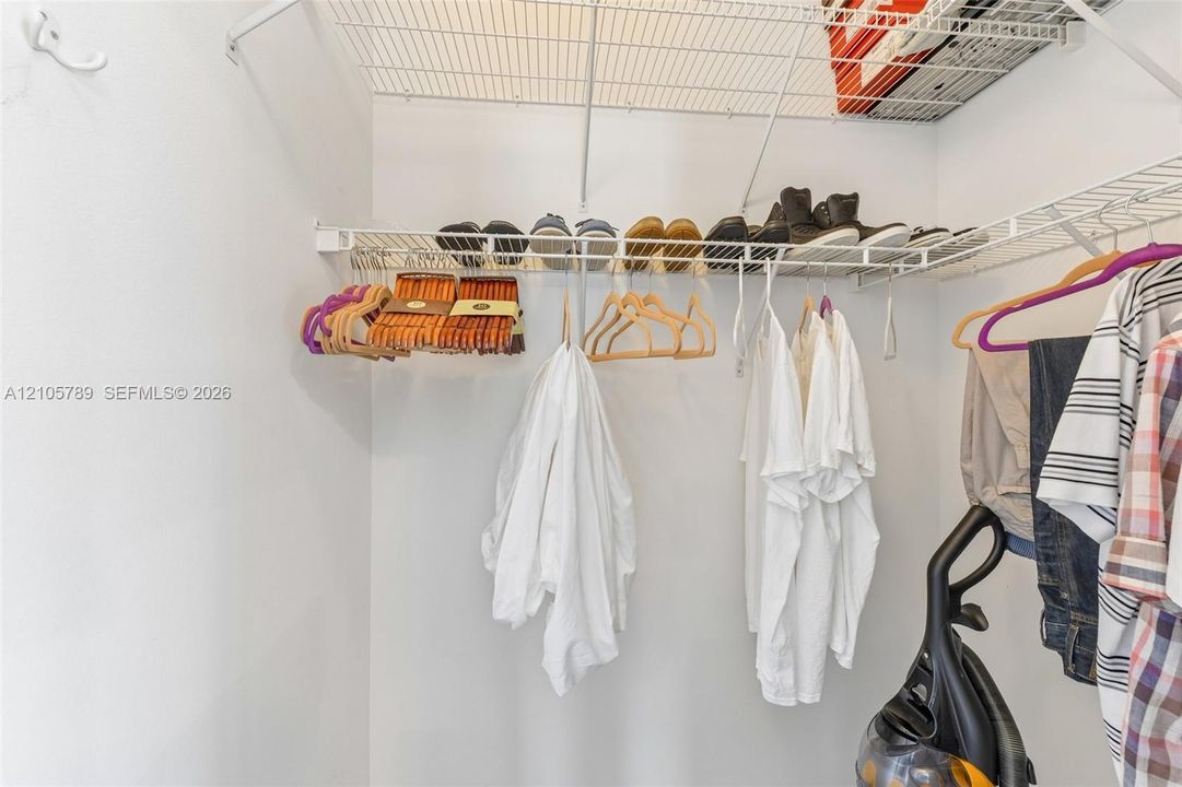 Walk-in closet featuring multi-level white wire shelving and a wall-mounted hook
