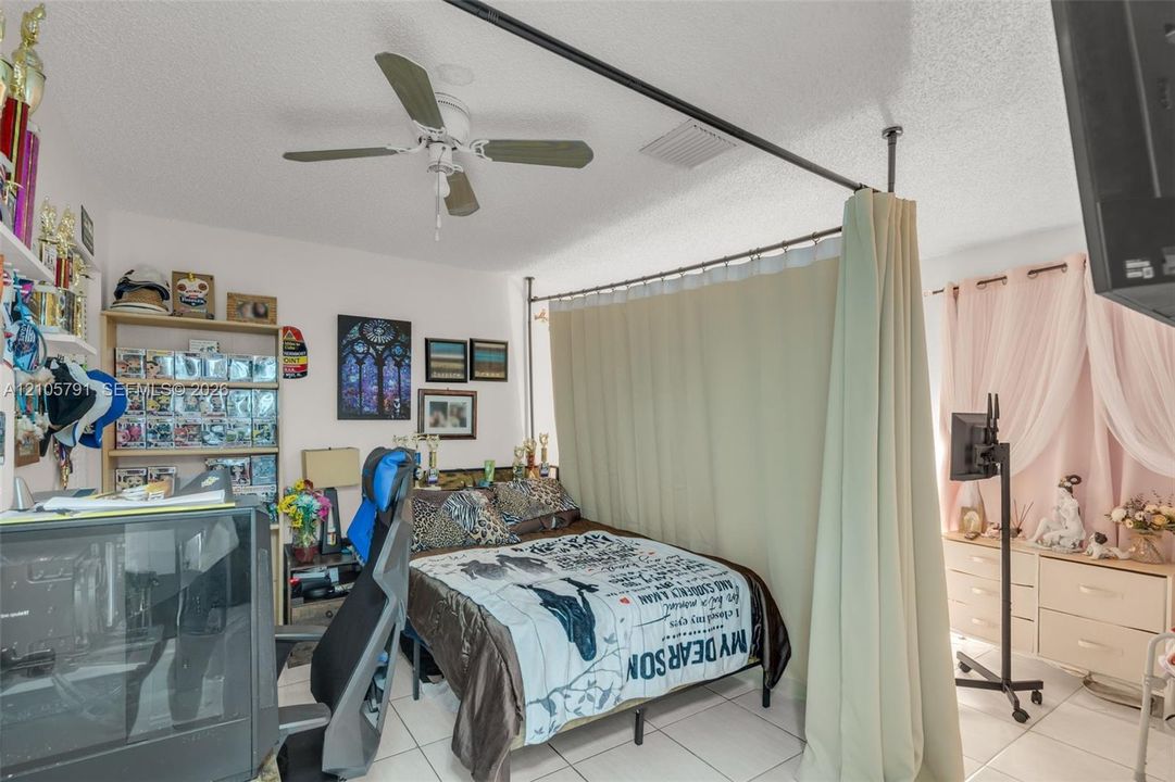 Room featuring tile flooring, ceiling fan, and built-in shelving