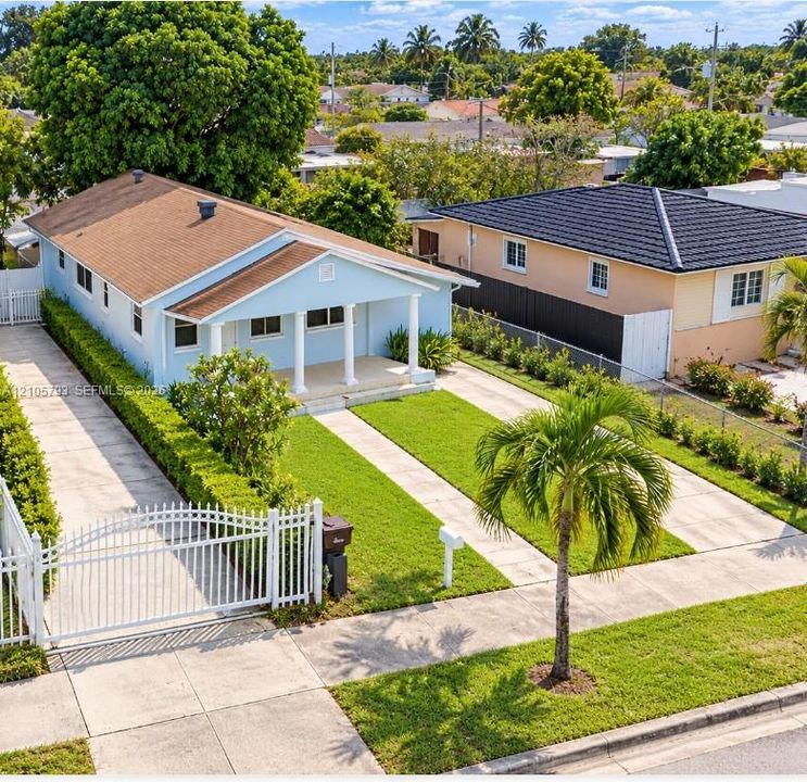 Single-story residence featuring a covered front porch with decorative columns, a concrete dual-entry driveway, and perimeter white metal fencing