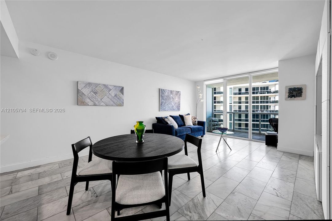 Open floor plan featuring large-format stone tile flooring and floor-to-ceiling glass sliding doors opening to a private balcony