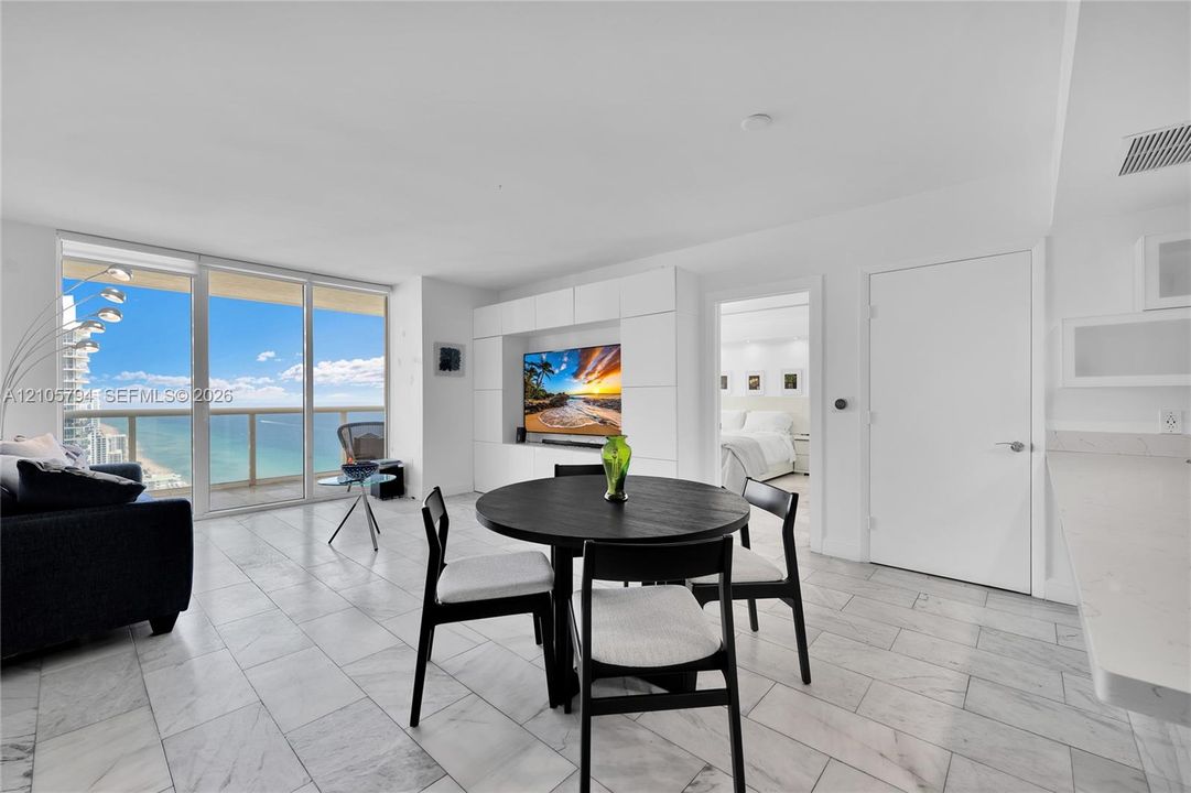 Open-concept interior featuring floor-to-ceiling glass paneling, tile flooring, and custom built-in cabinetry