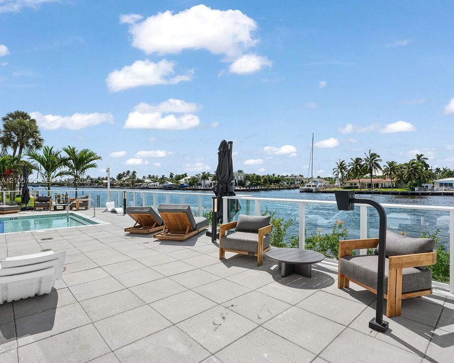 Waterfront terrace featuring a tiled deck, built-in pool, and glass railing system overlooking the canal