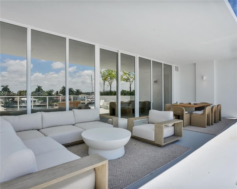 Covered terrace featuring floor-to-ceiling glass wall panels, minimalist structural columns, and a smooth, level ceiling finish