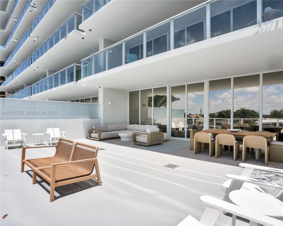 Expansive terrace featuring glass balcony railings, floor-to-ceiling sliding glass doors, and a solid wall perimeter